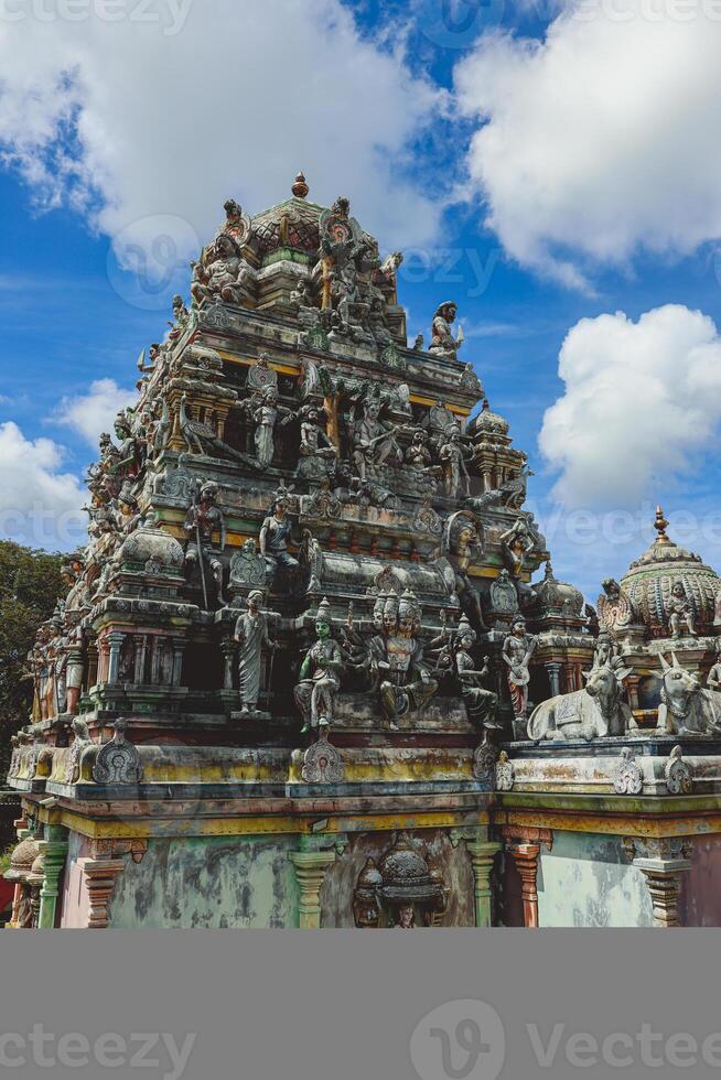 A tall tower featuring intricately carved statues at an Indian temple. photo