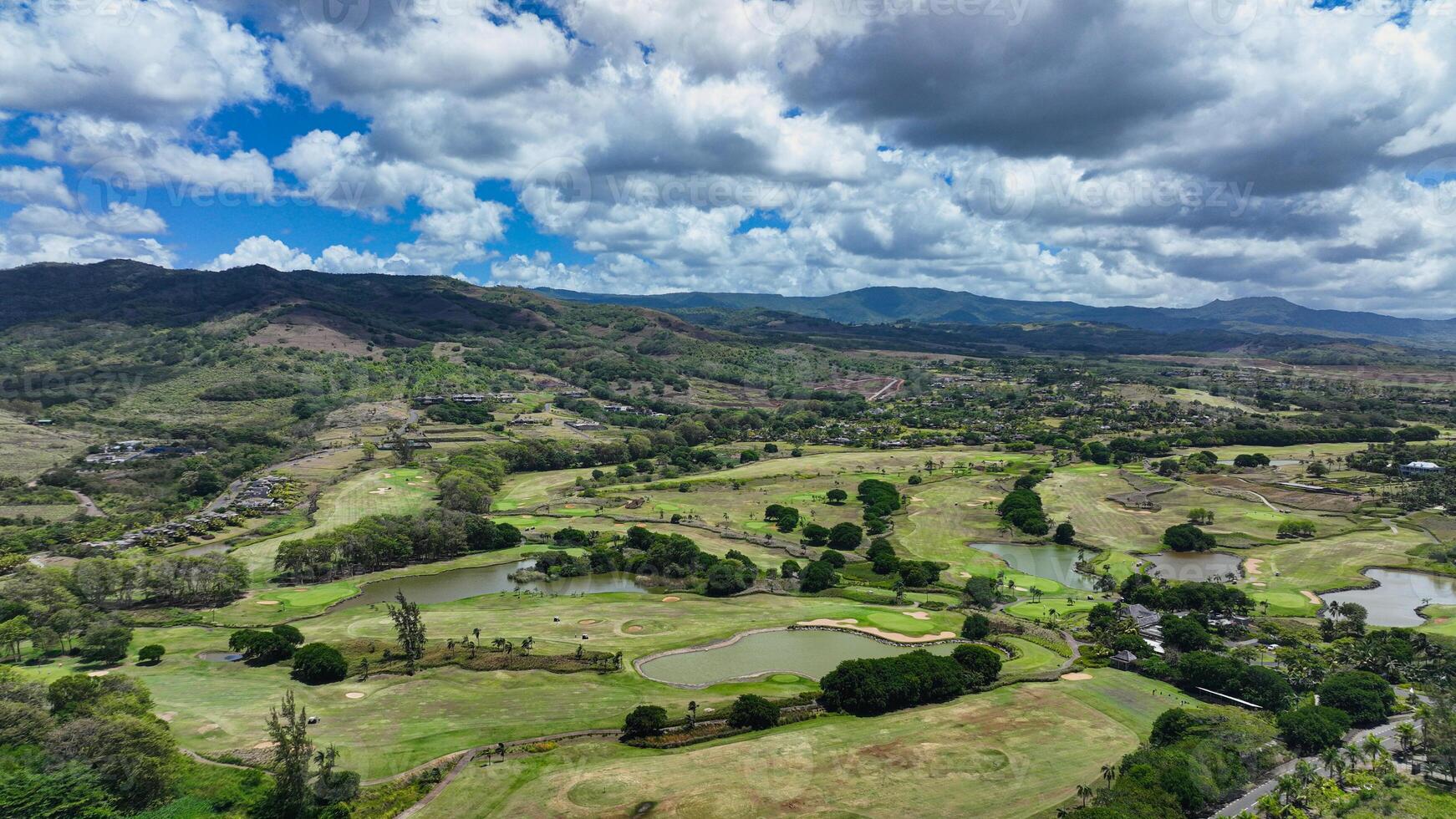 This aerial photograph showcases a golf course in Mauritius, with the fairways and greens beautifully laid out amidst a surrounding expanse of water. photo