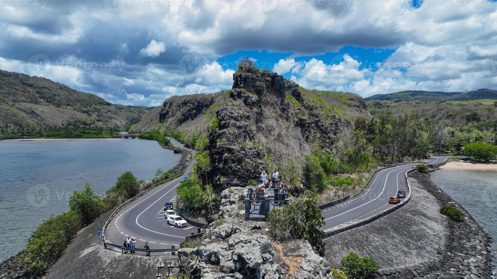 An aerial view captures a winding road as it travels towards the ocean, showcasing the interaction between man-made infrastructure and the natural environment. photo