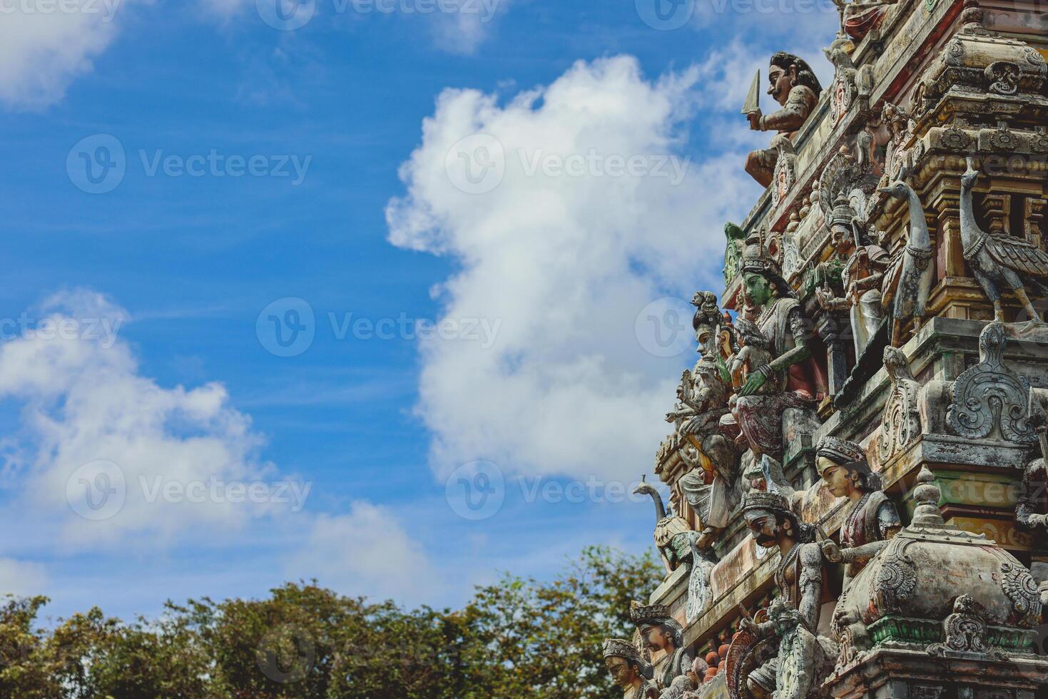 A tall tower featuring intricately carved statues at an Indian temple. photo