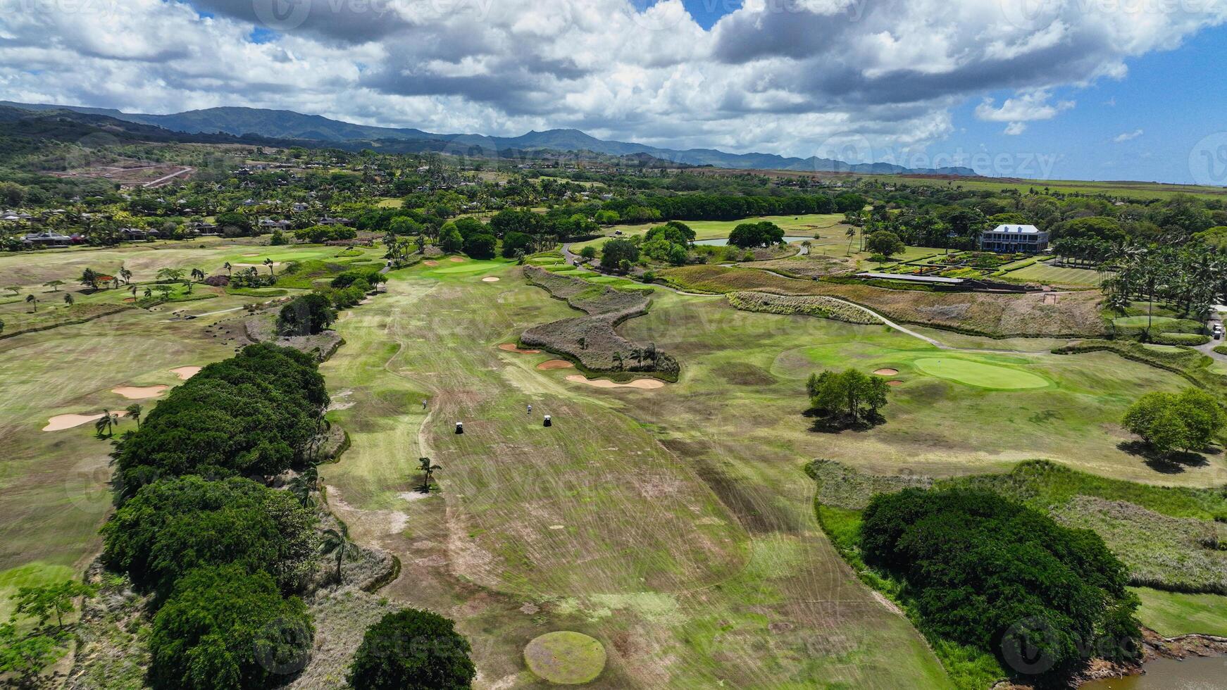 This aerial photograph showcases a golf course in Mauritius, with the fairways and greens beautifully laid out amidst a surrounding expanse of water. photo
