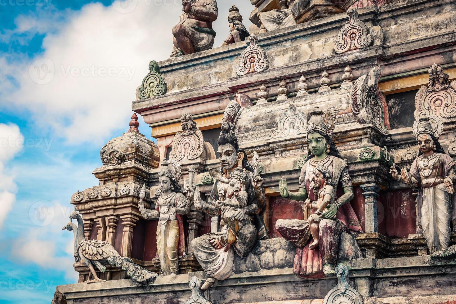 A tall tower featuring intricately carved statues at an Indian temple. photo