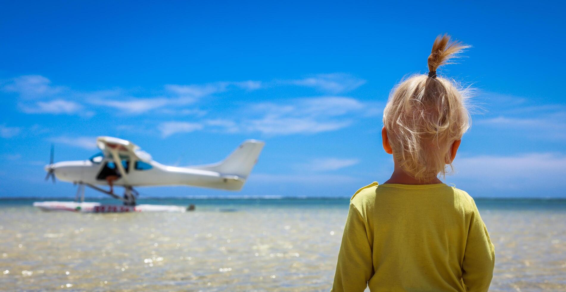 A little boy stands confidently in front of an airplane at the Mauritius beach photo