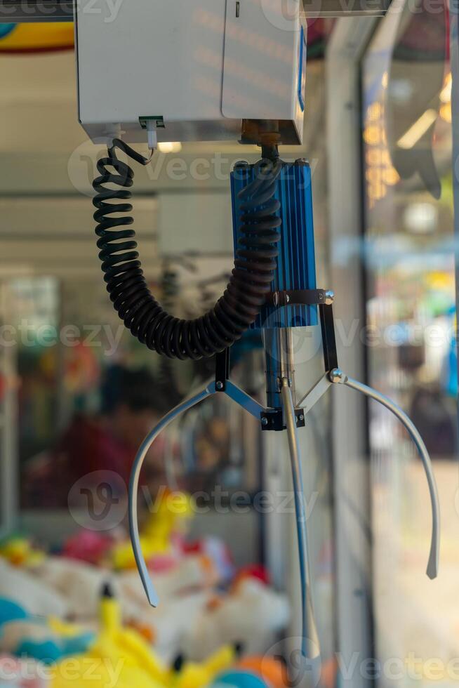 claw machine with a blue and black claw is hanging from the ceiling photo