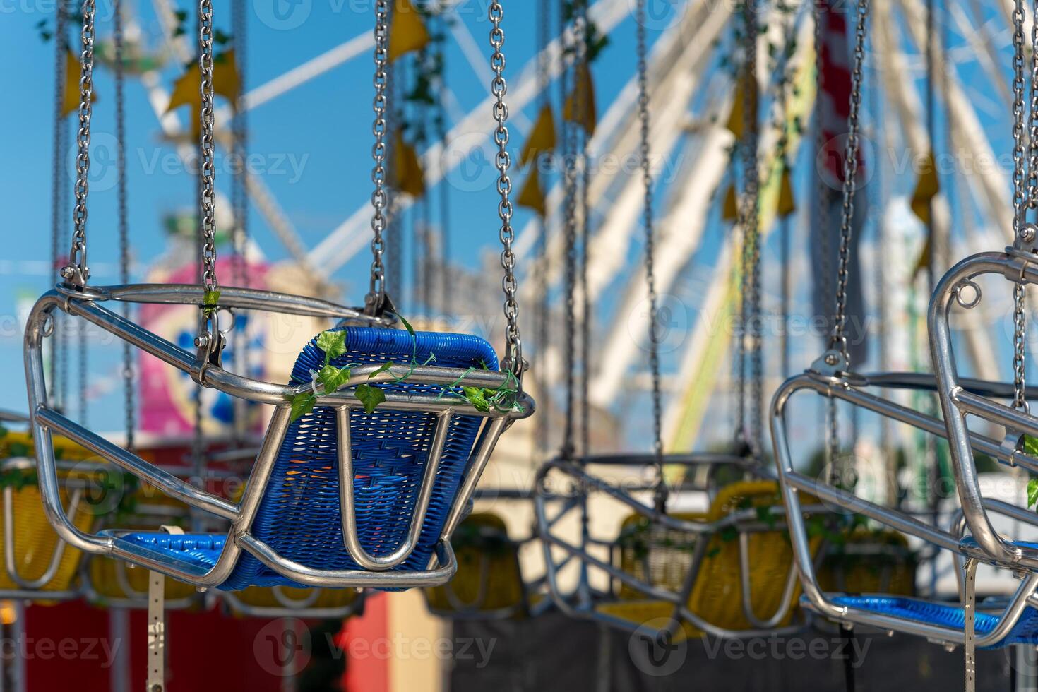 row of swings with green and blue seats hanging from a chain photo