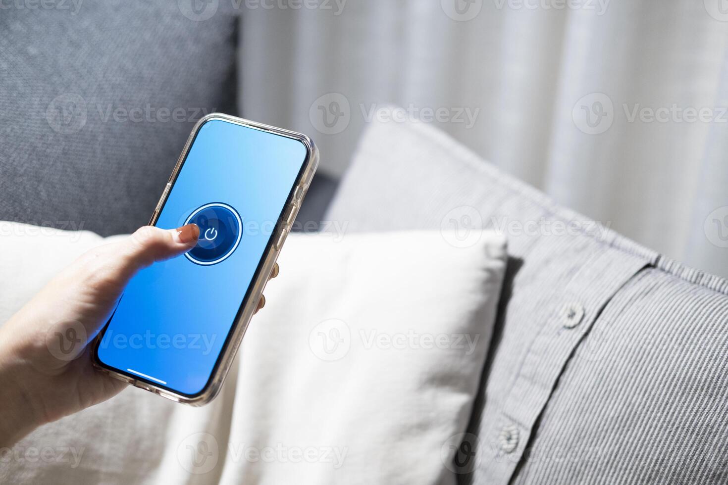 Smart home concept Controlling lights, lamps, or home appliances through a mobile application. A woman's hand is turn off the lights through her phone on the bed or sofa in the house photo