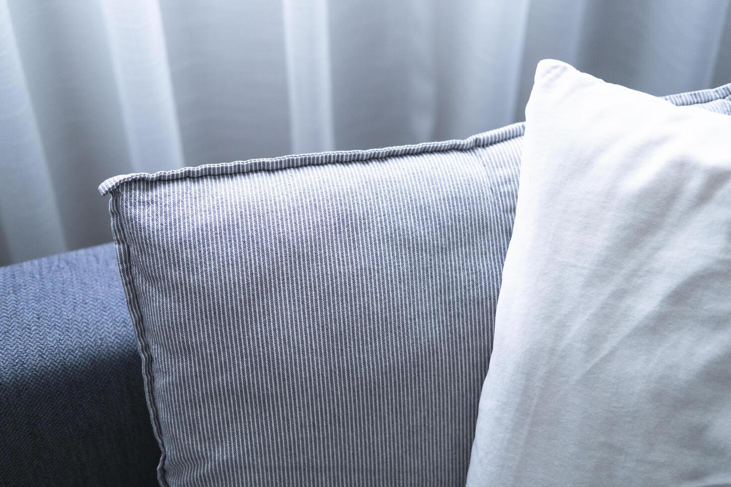 Close-up of cushions on cozy grey sofa. Modern interior of living room. with large window and sheer curtain. photo