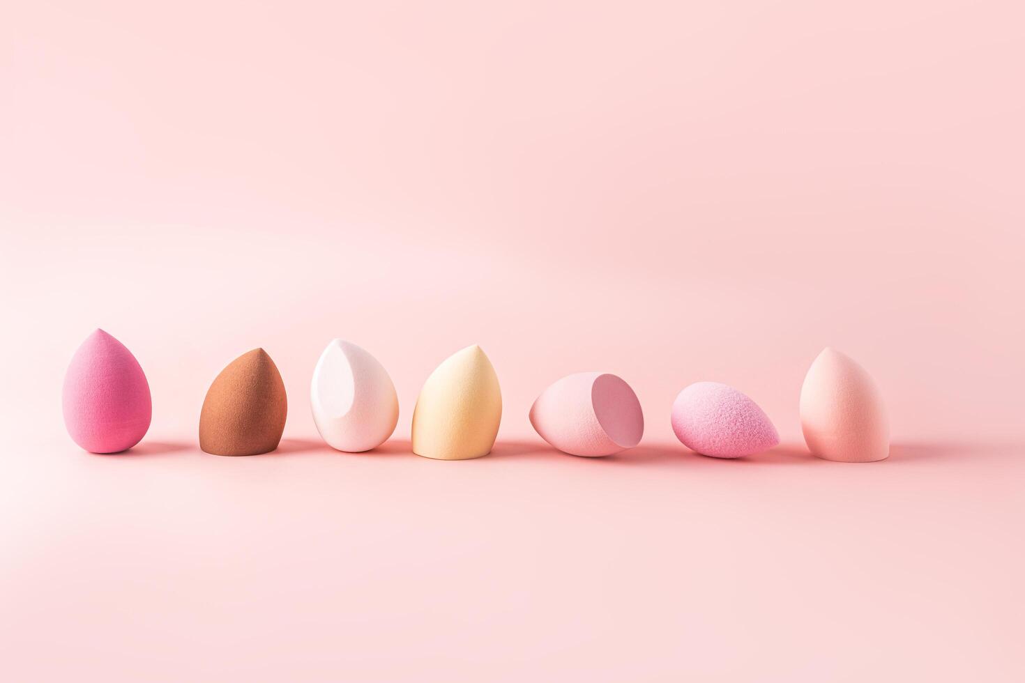 Cosmetic beauty Blender Sponge Set in various colors in pink tone lined up. pink background. Front view. liquid cosmetics application tool. photo