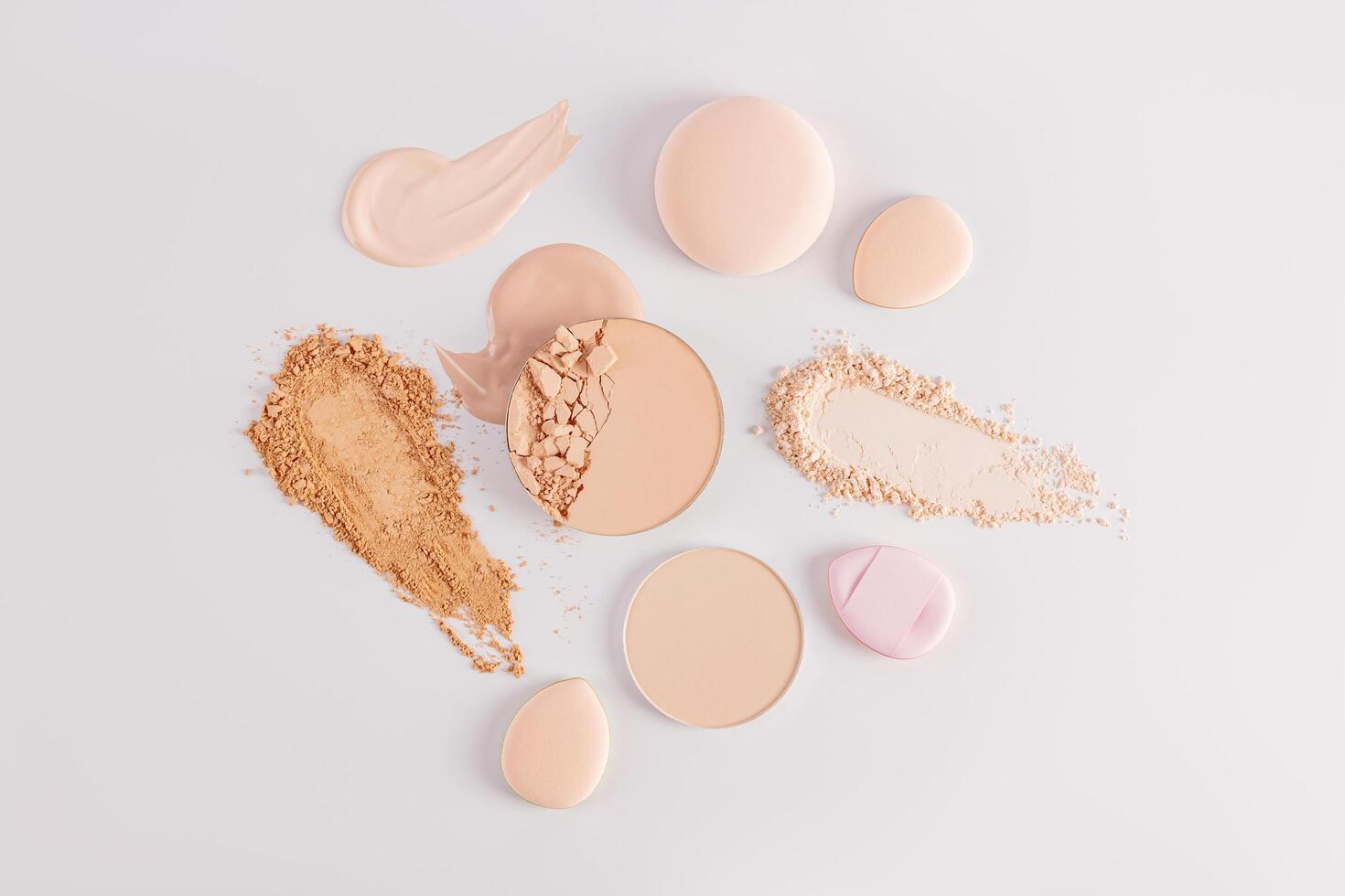 Samples of compact powder and loose powder of different tones, strokes, blocks, sponge on a white background. top view. texture of various powders. photo