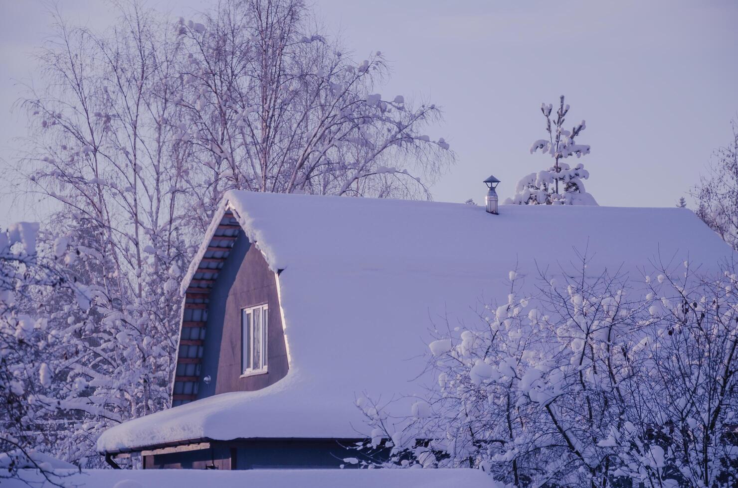 The roof of the house in winter is covered with snow photo