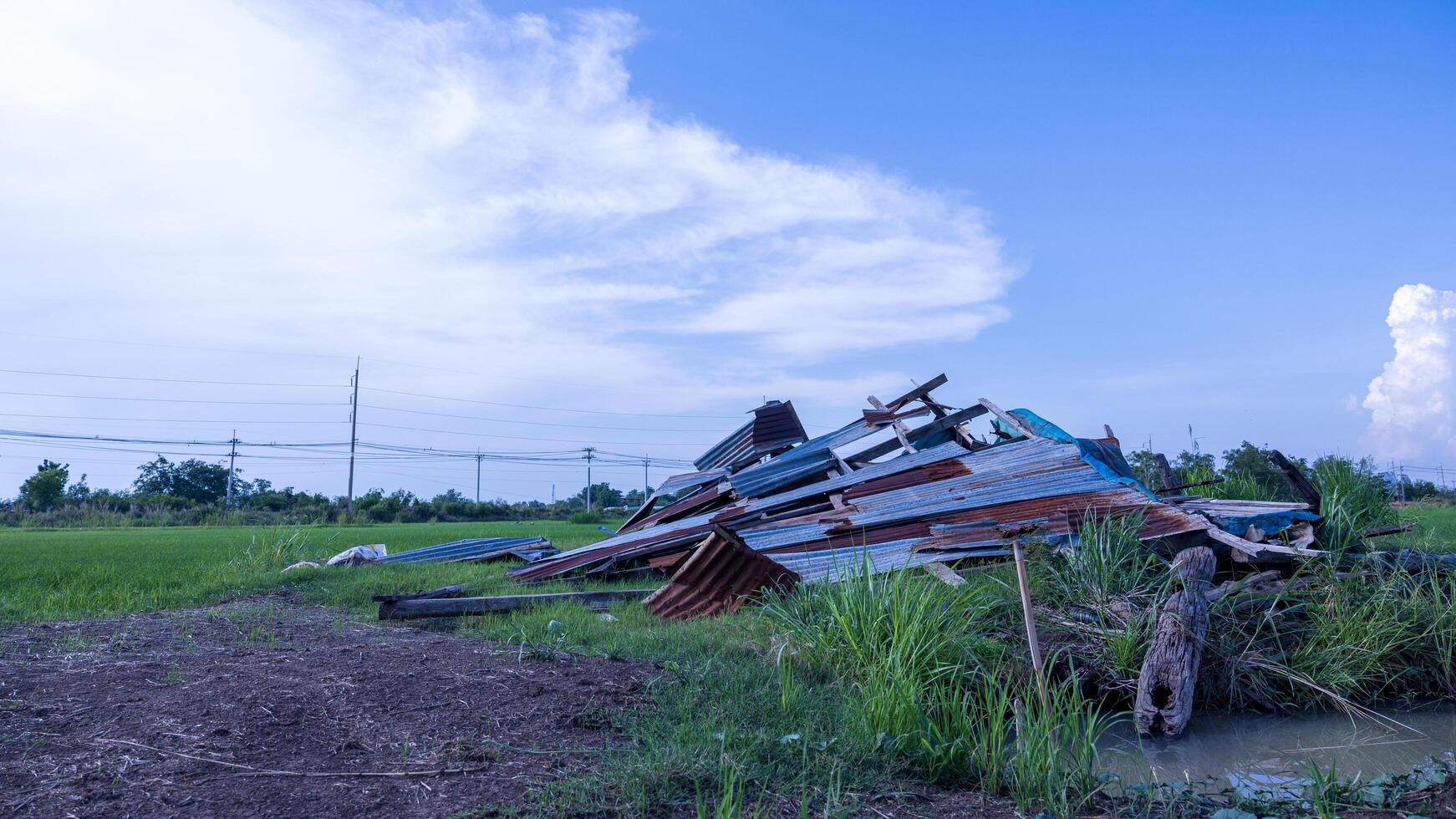 A view of an old wooden hut with a zinc sheet roof collapsed. photo