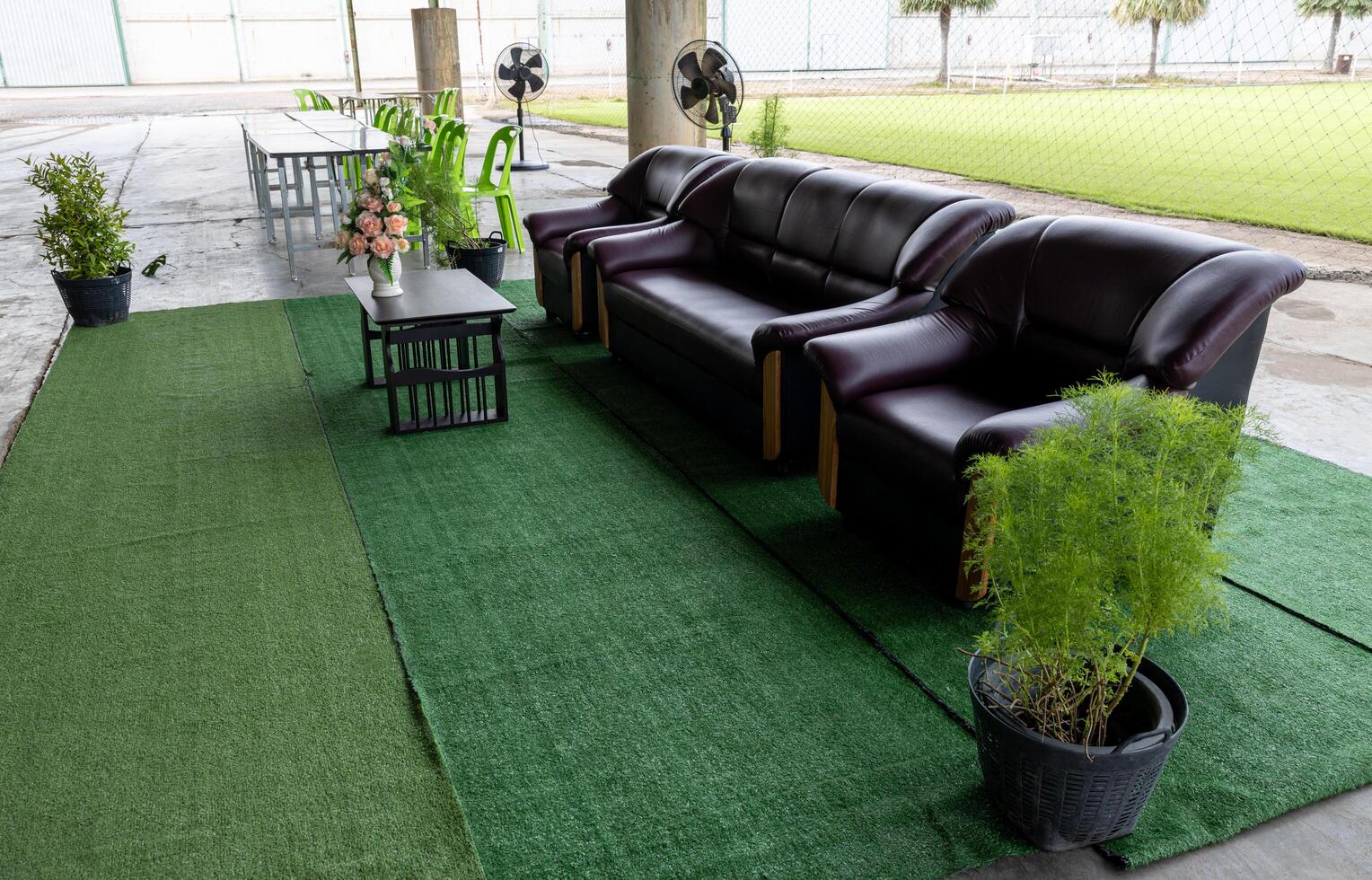 Three brown sofa seats are set up on green artificial grass. photo