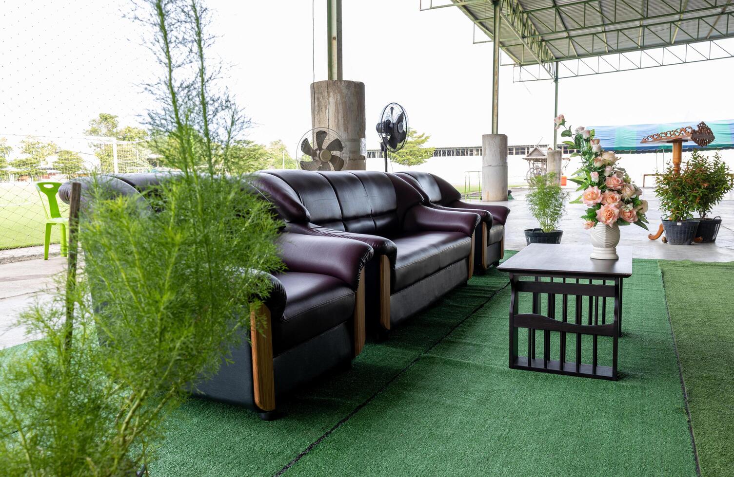 Three brown sofa seats are set up on green artificial grass. photo