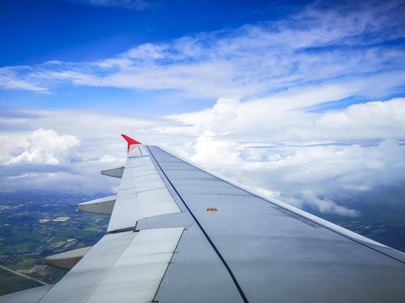wings of airplane during the flight look from the passenger window. There are white clouds in the blue sky. photo