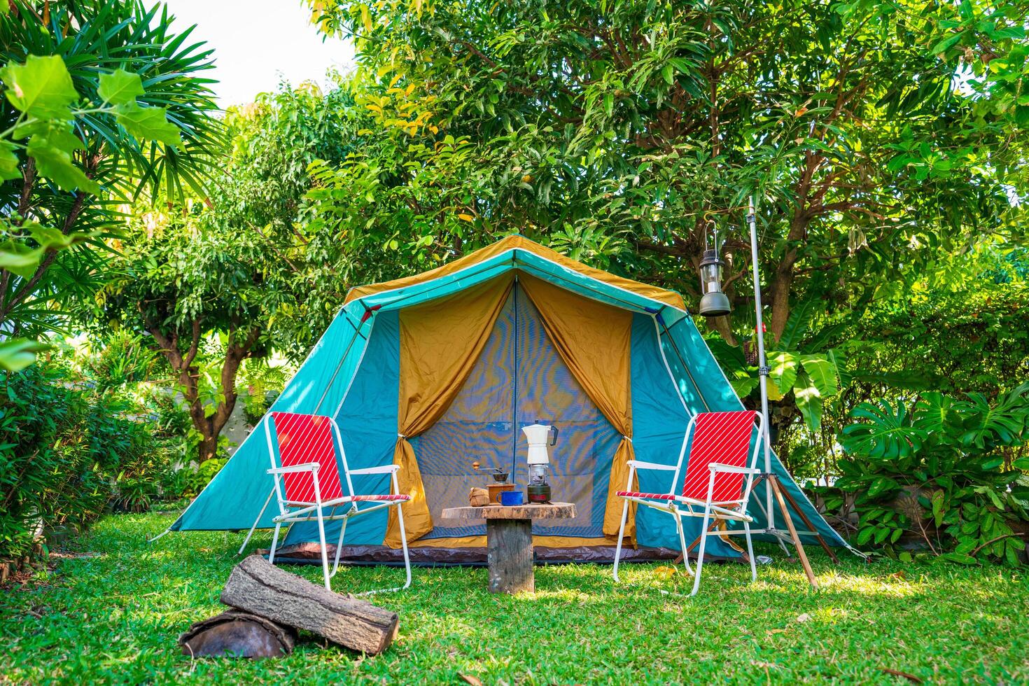 Camping tents, vintage cabin tents, Antique lanterns, retro chairs, and outdoor coffee-making facilities on wooden tables in a forest photo