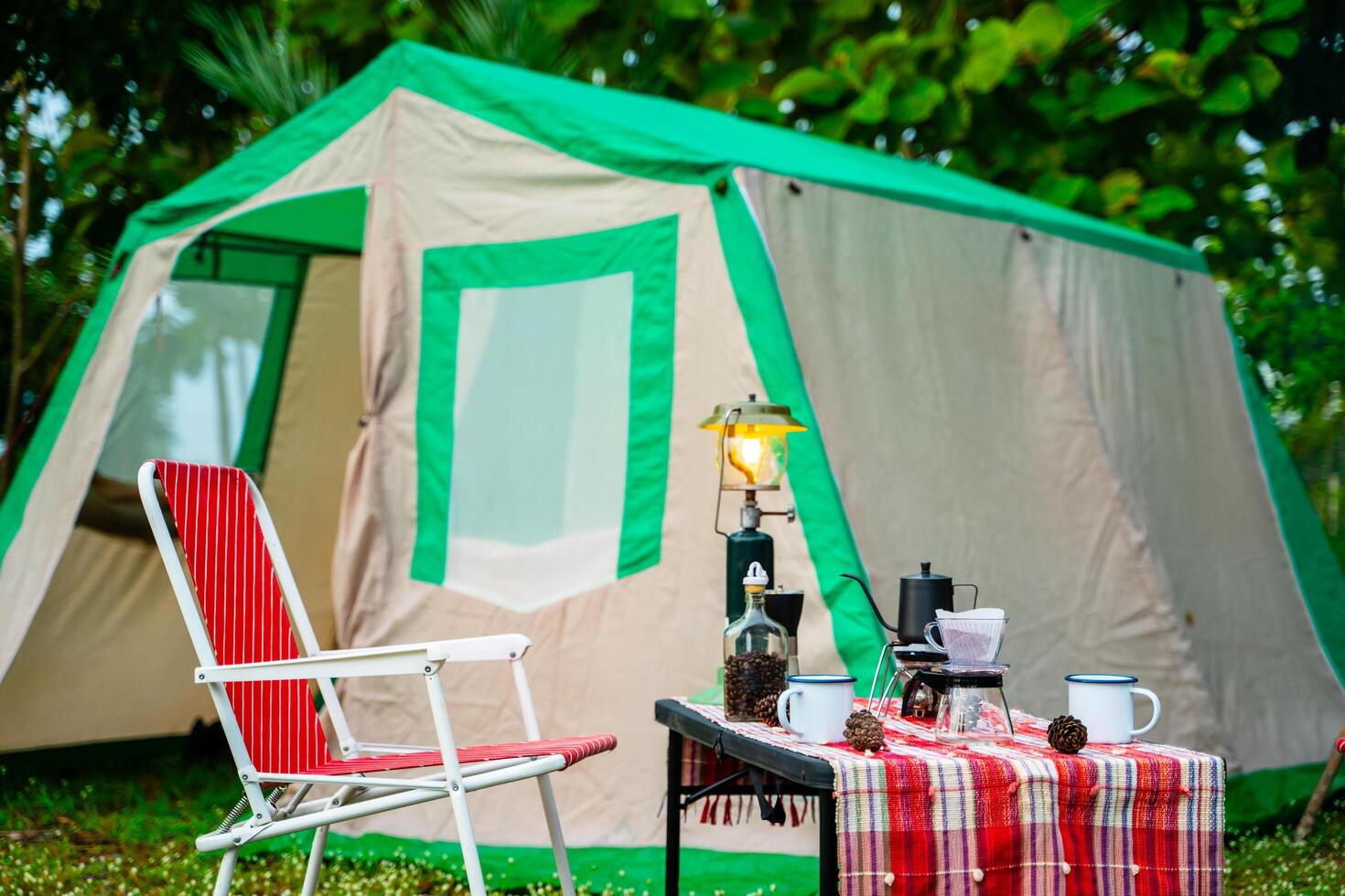 selective focus of vintage coffee set on the old wooden table In front of the retro cabin tent, retro chairs, Group of camping tents, and soft focus. photo