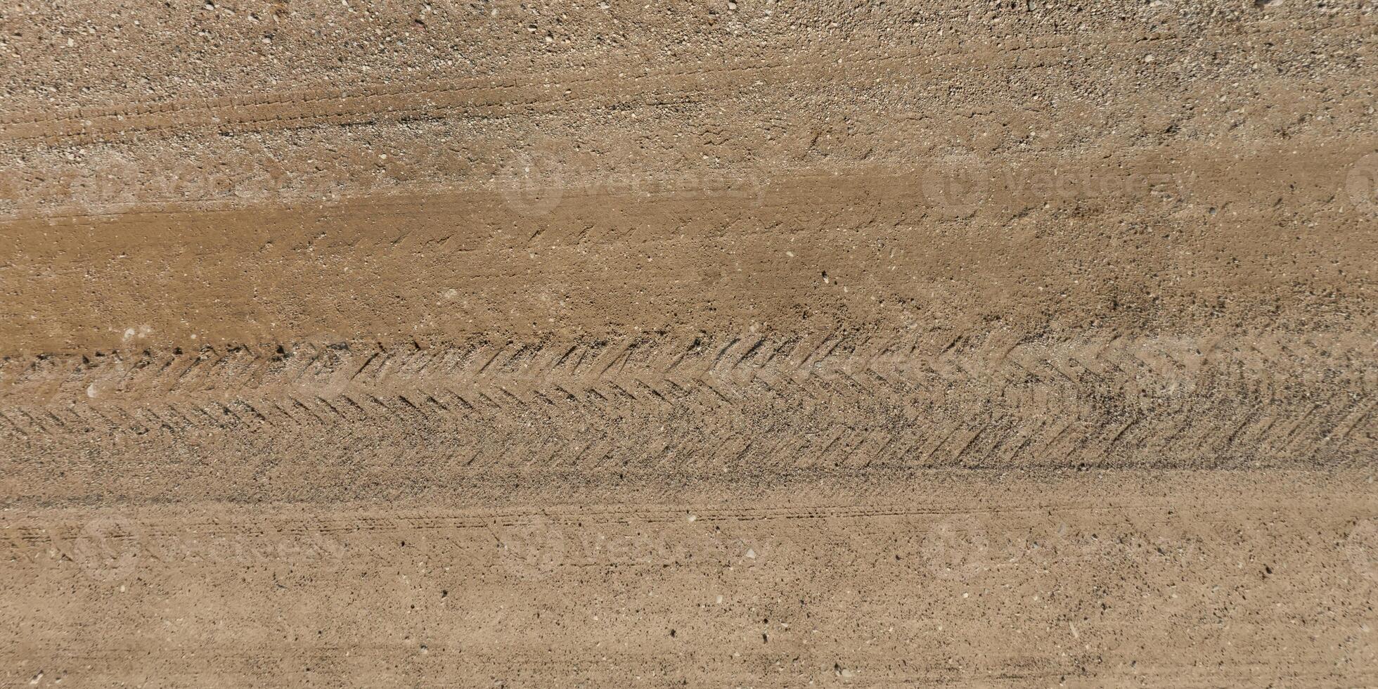 view from above on texture of dry muddy road with tractor tire tracks in countryside photo
