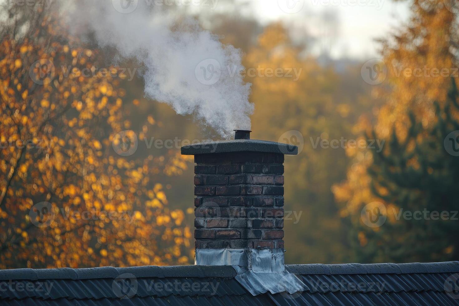 Brick chimney releasing smoke from burning wood in fireplace on autumn day photo