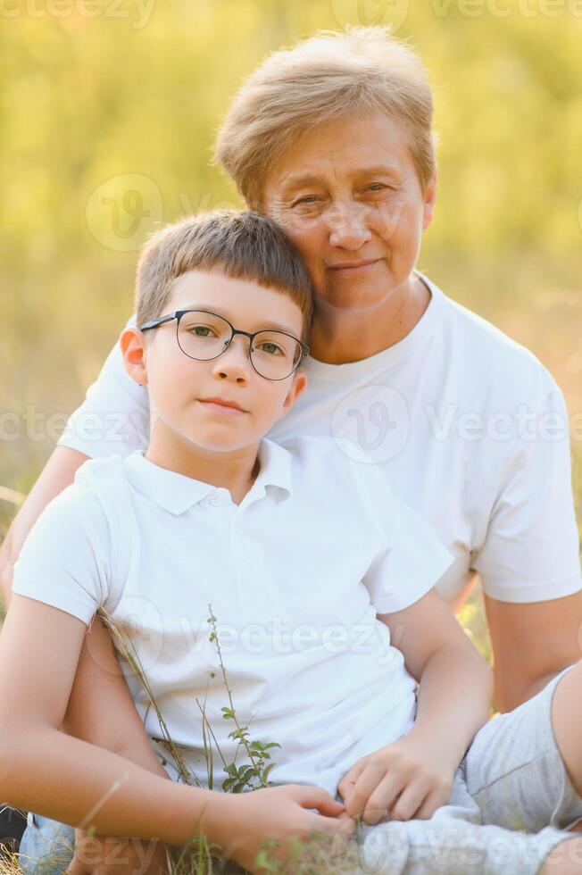 Grandmother walking with her grandson. Relaxing and joying in sunset photo