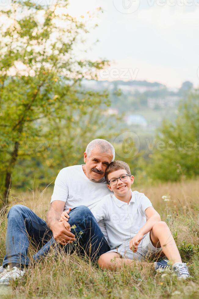 Portrait of happy grandfather and grandson in autumn park photo