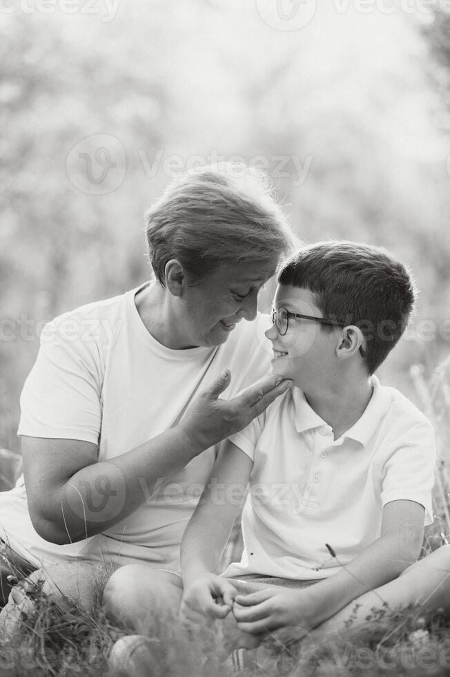 A beautiful grandmother spends time with her grandson in nature at sunset photo