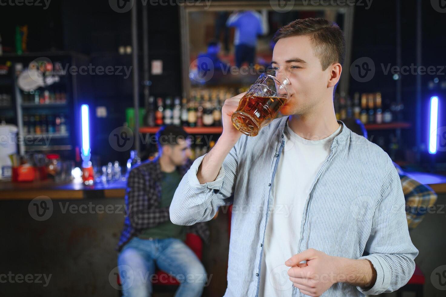 Night in bar. Portrait of cheerful men drinking beer at the bar photo