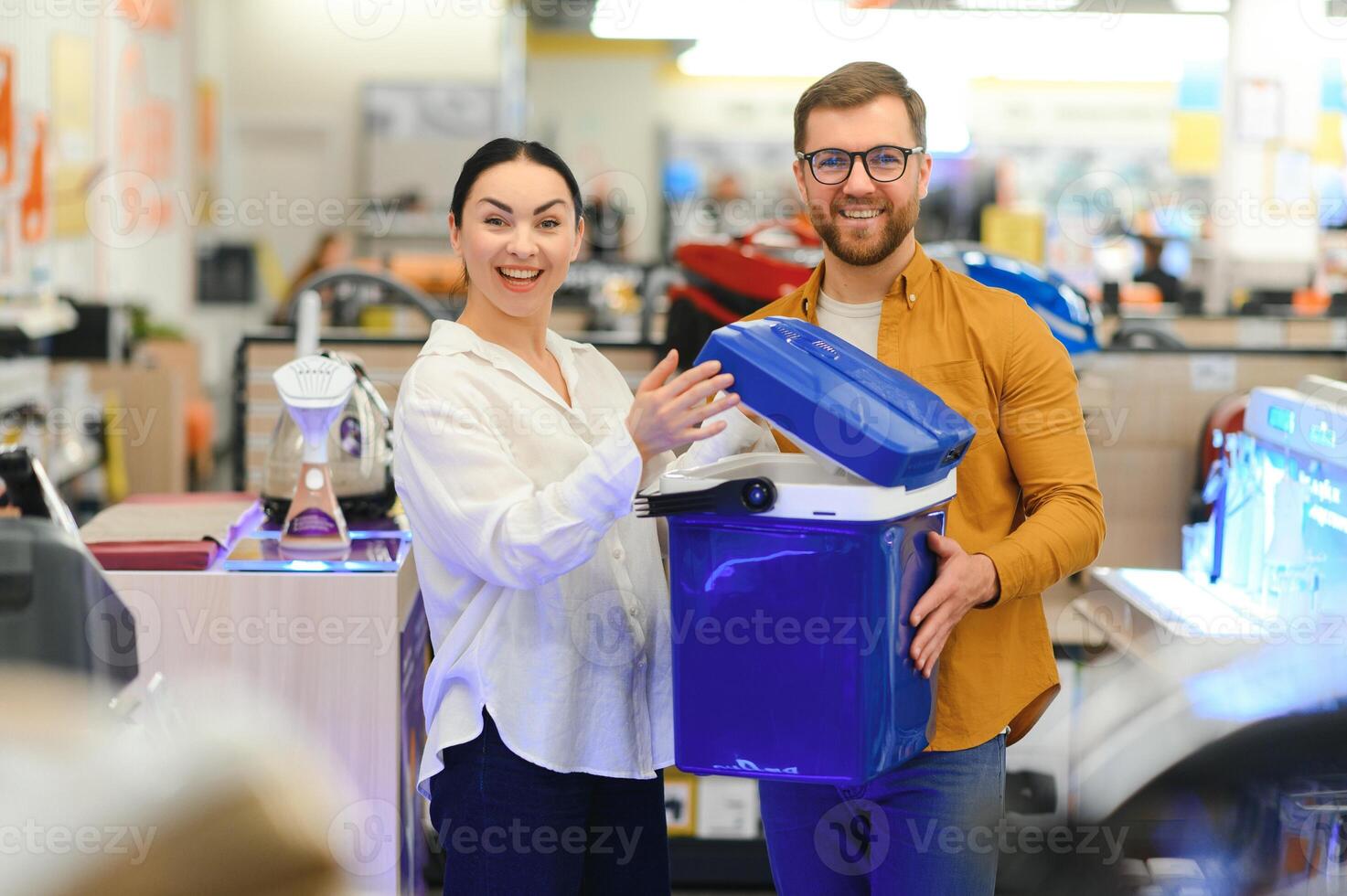 A young couple buys a portable refrigerator in an electronics store photo