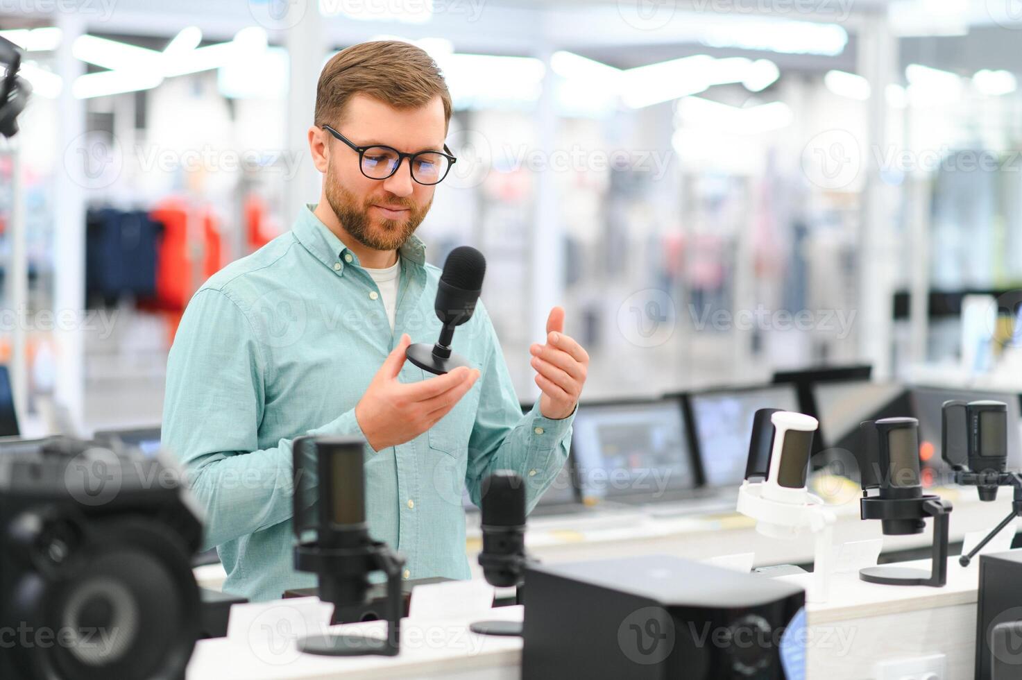 A man chooses a professional microphone to record a blog. Electronics store photo