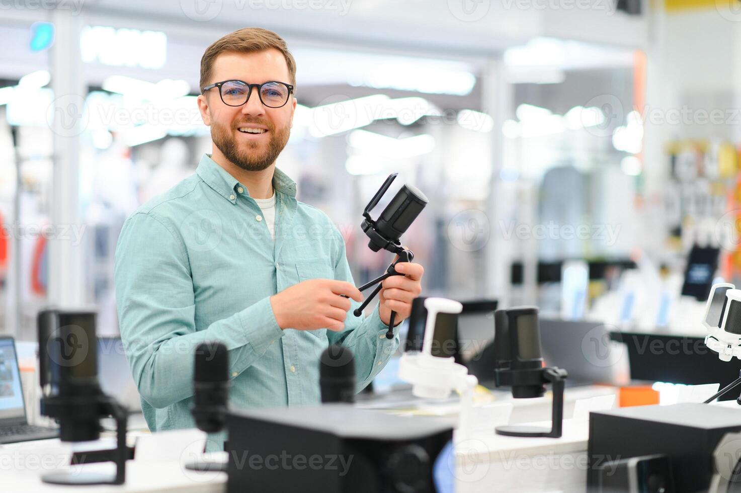 A man chooses a professional microphone to record a blog. Electronics store photo