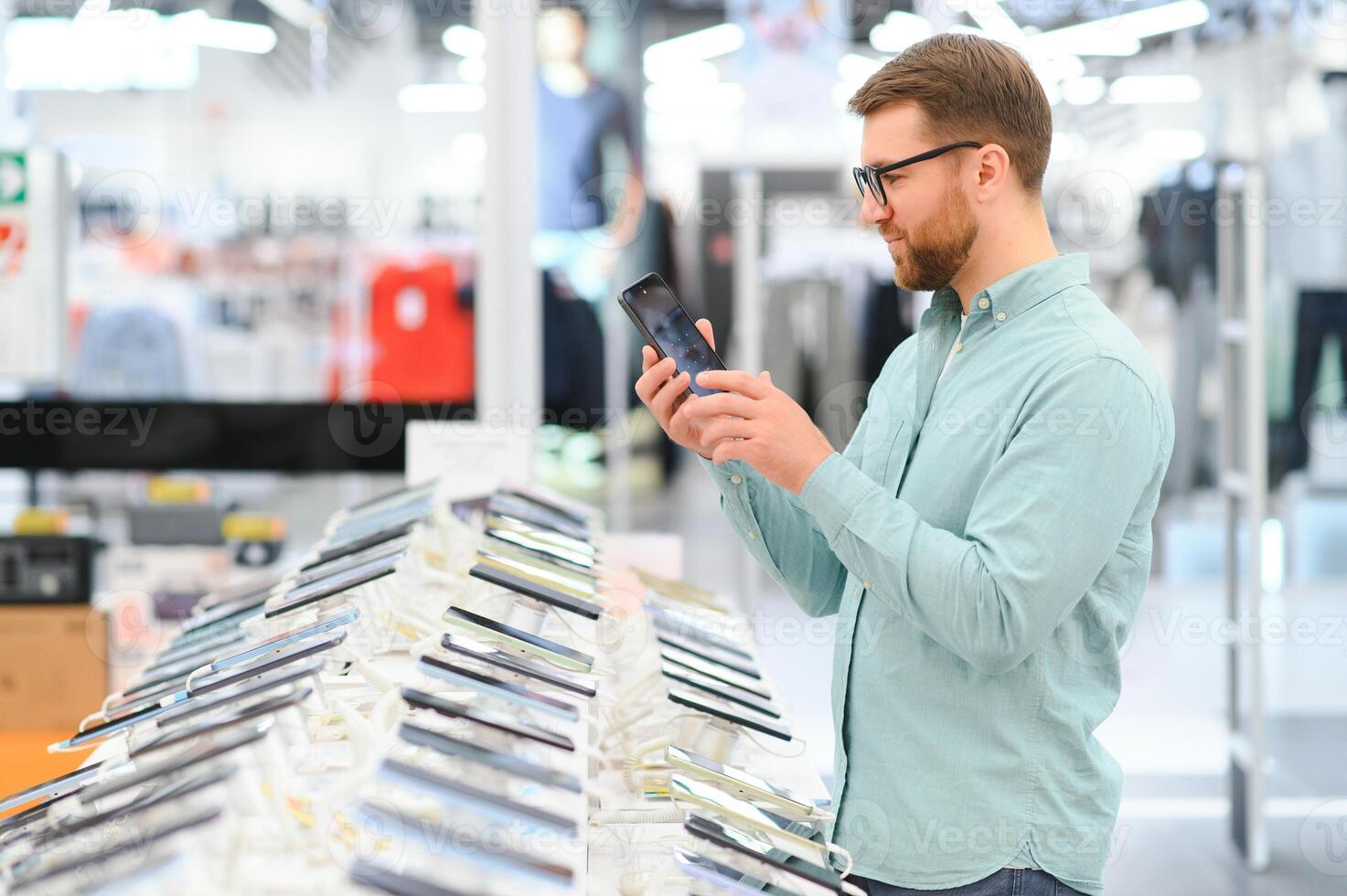 happy young man choosing a new mobile in a tech store photo