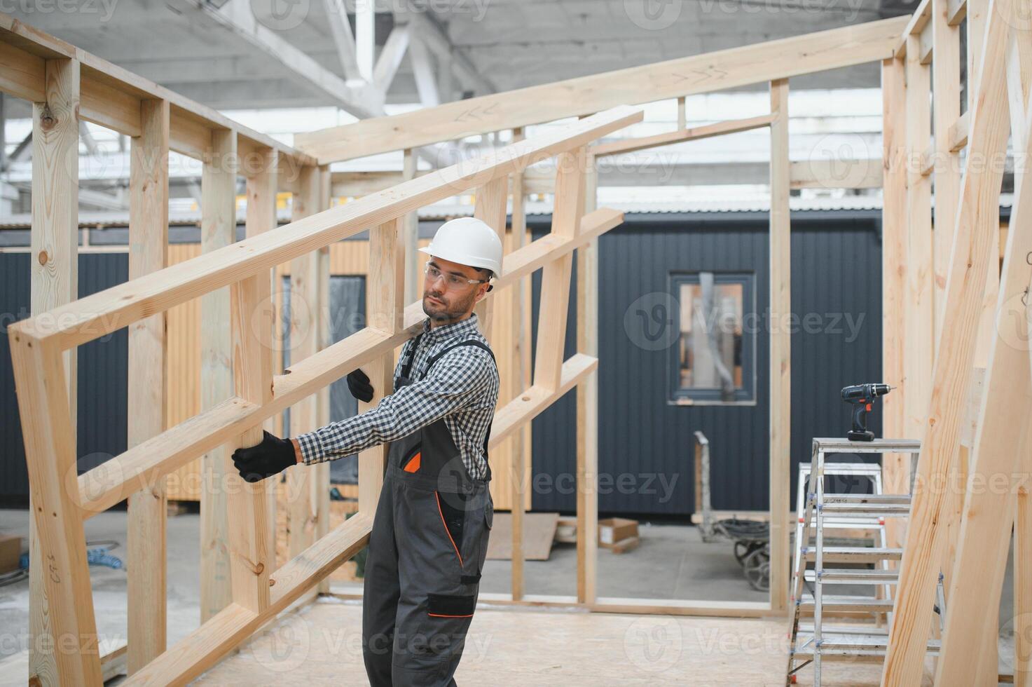 Portrait of a young carpenter worker in a helmet at the construction site of modular houses photo