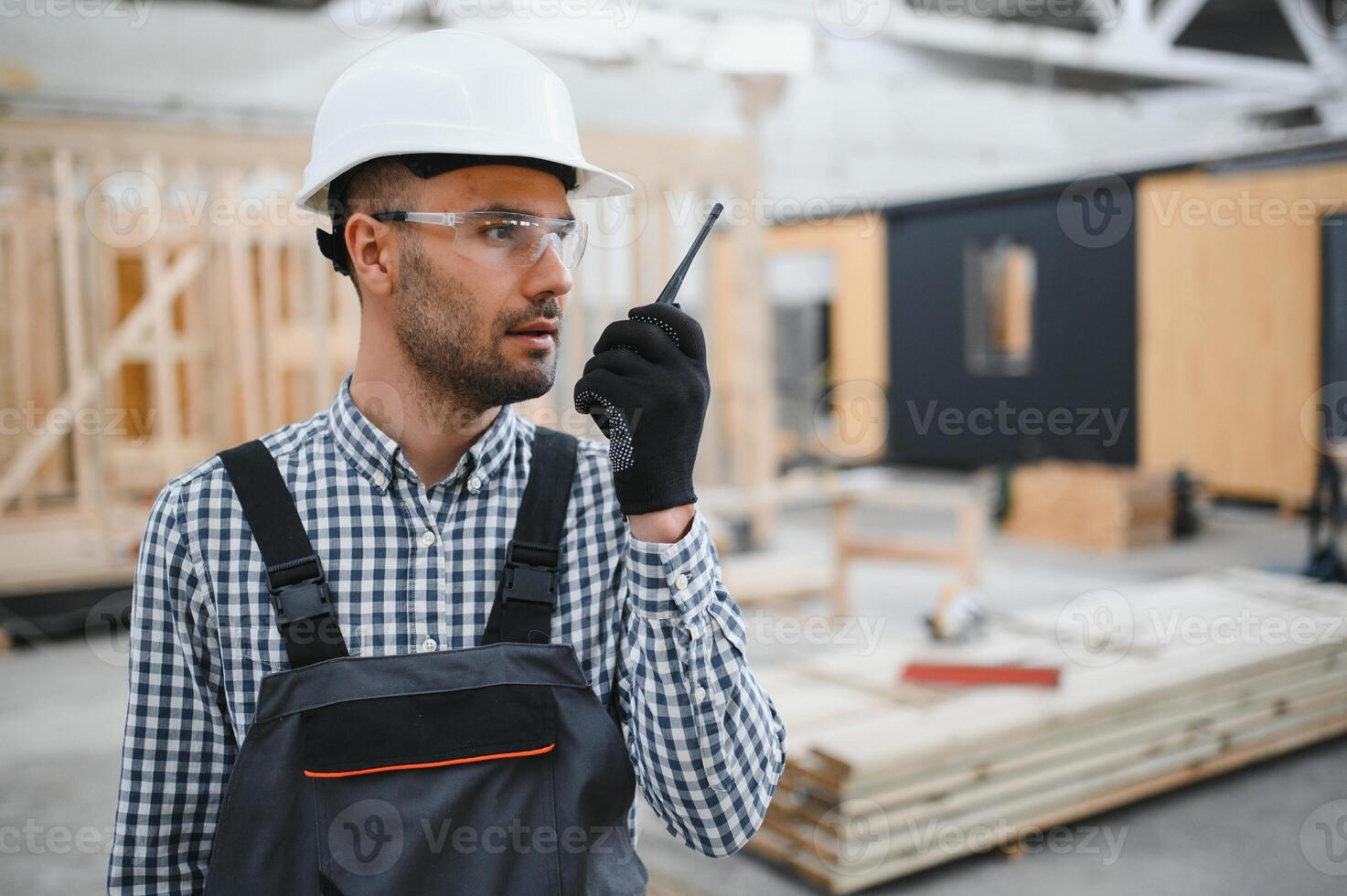 An engineer controls the production of modular houses and uses a walkie-talkie photo