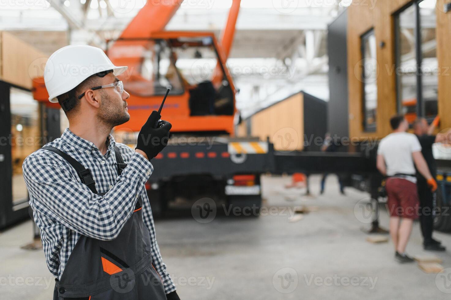 Foreman manages the loading of a prefabricated modular house to truck using walkie talkie photo