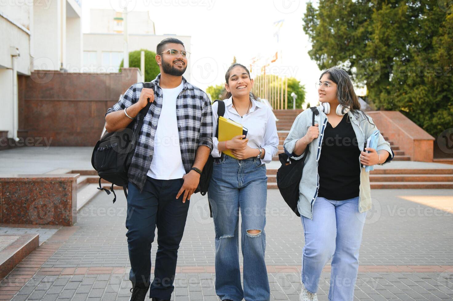 Three international students standing and holding a books photo