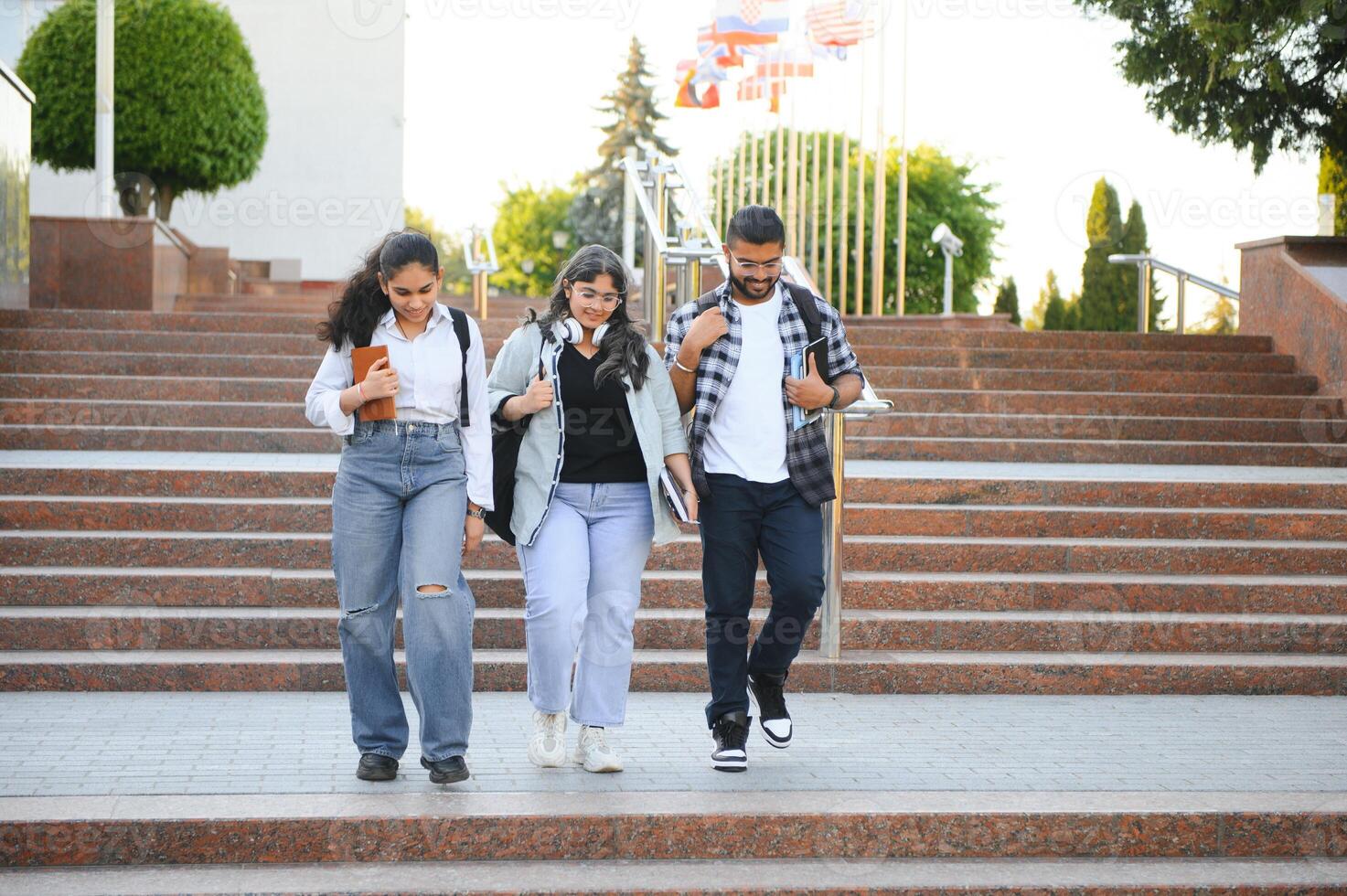 Three international students standing and holding a books photo