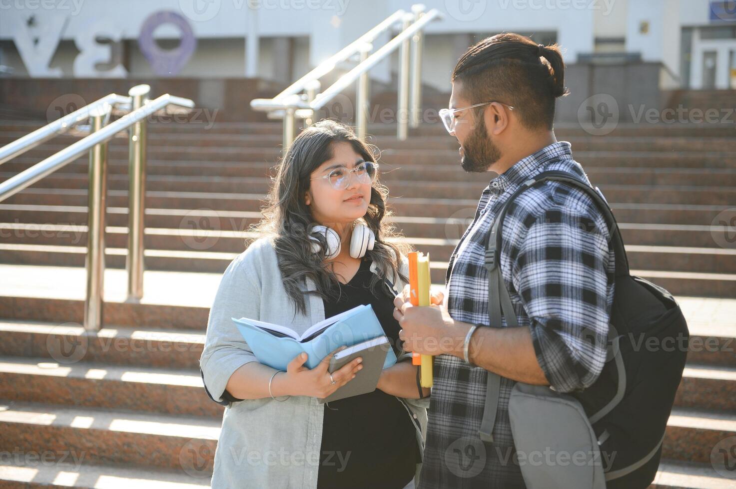 Three international students standing and holding a books photo