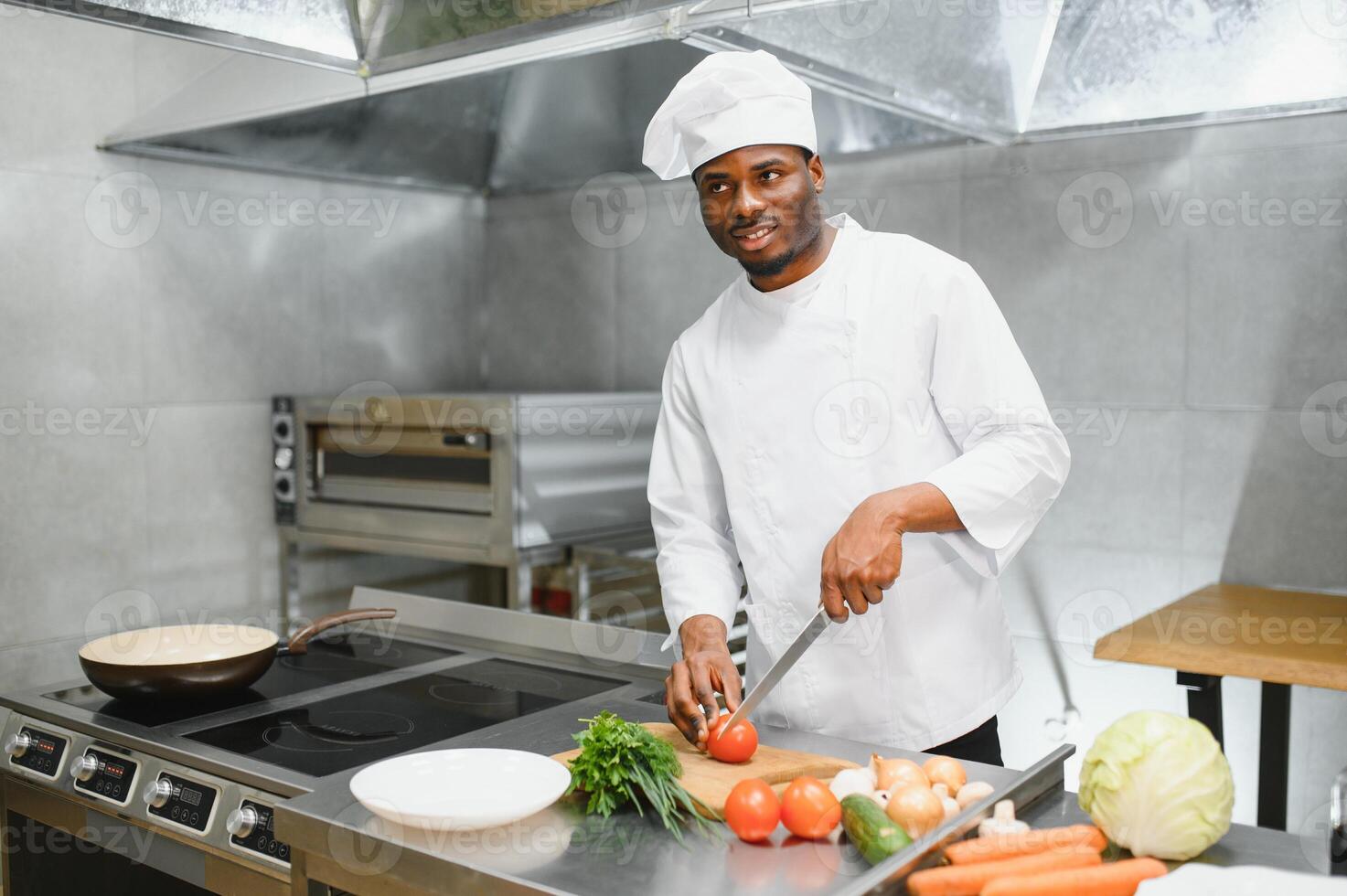 Portrait of happy African American male chef standing in restaurant kitchen photo