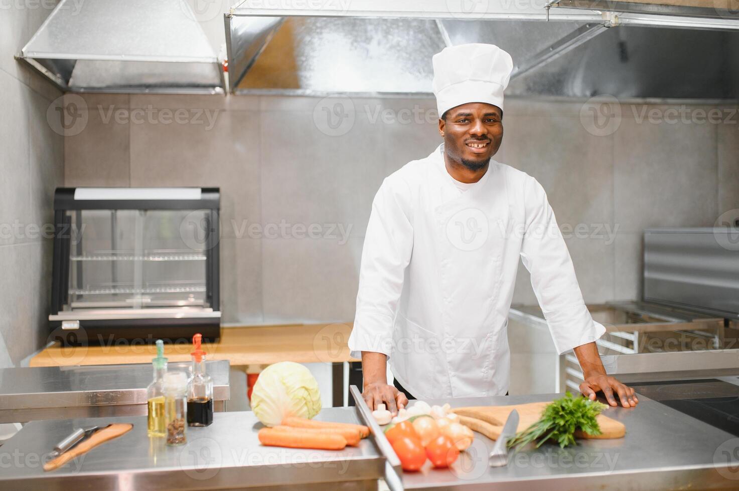 Portrait of happy African American male chef standing in restaurant kitchen photo