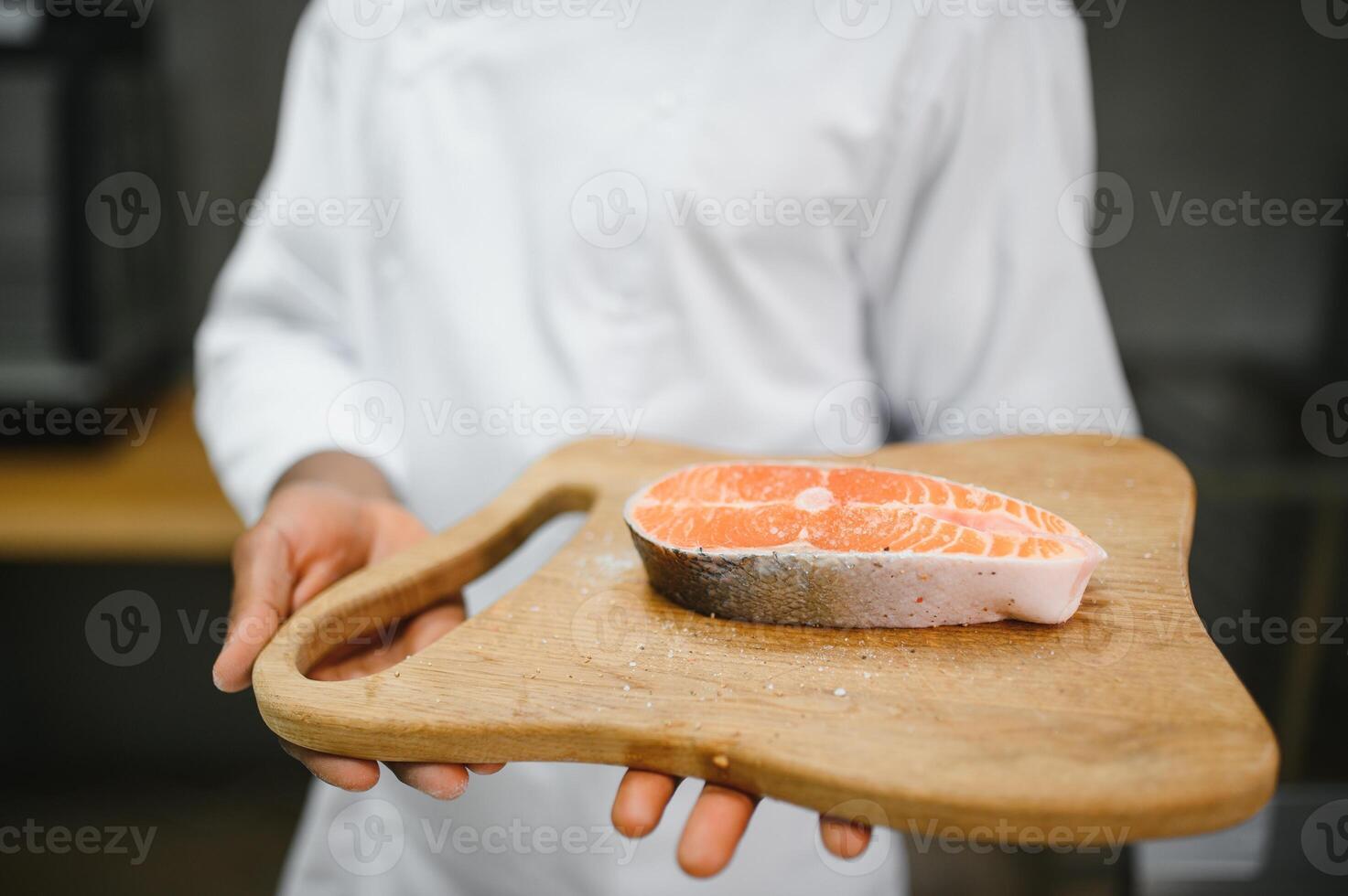African American male chef preparing salmon fish in restaurant kitchen photo