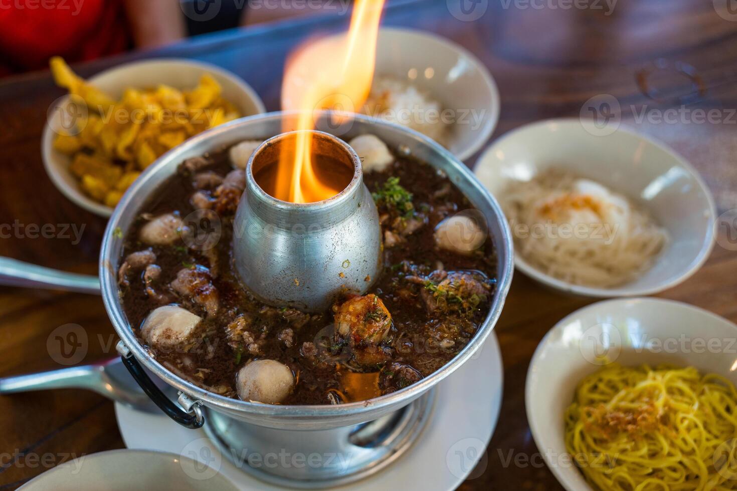 Thai beef soup with braised beef, sliced beef, meatball and vegetable served in fire hot pot photo