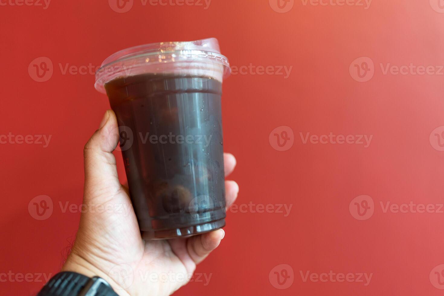Holding disposable iced black coffee in plastic cup photo