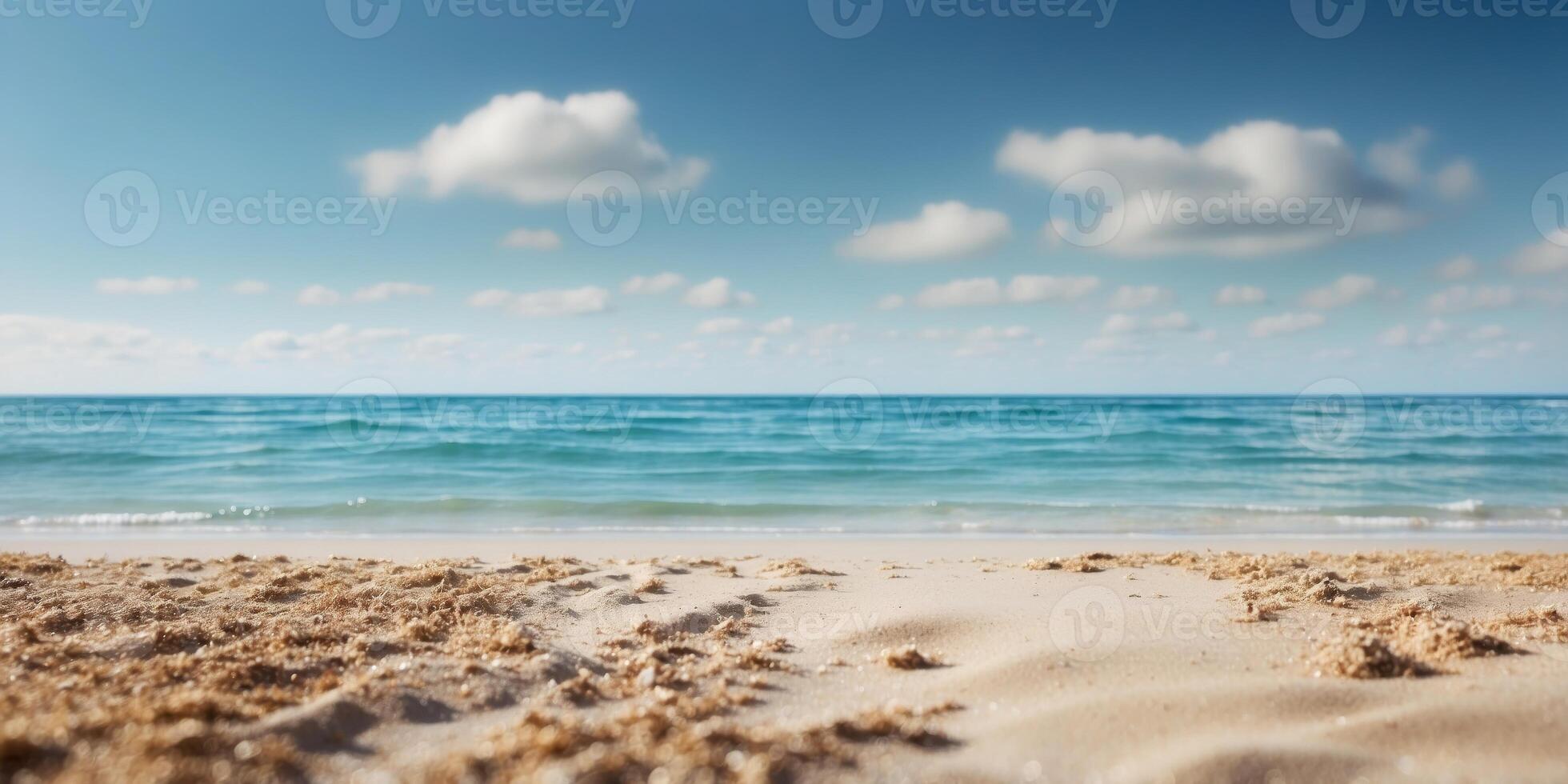 A sandy beach borders a body of water, with a blue sky dotted with clouds above. photo