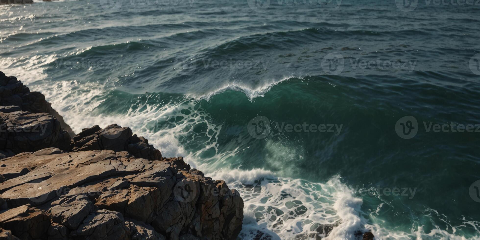 A large body of water sits next to a rocky cliff Waves regularly crest atop the water's surface. photo