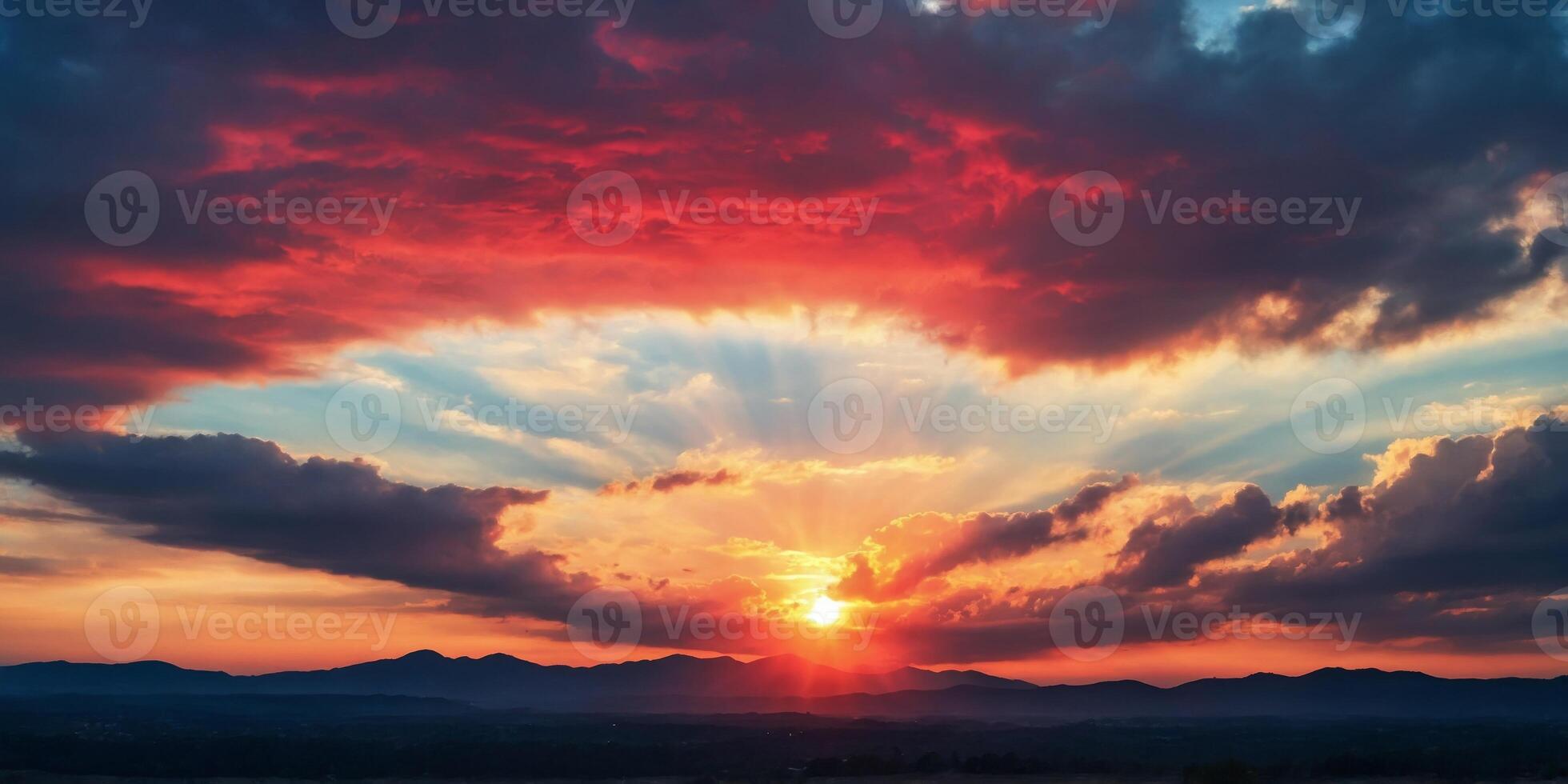 The sun shines through red and blue tinged clouds in a darkened sky. photo