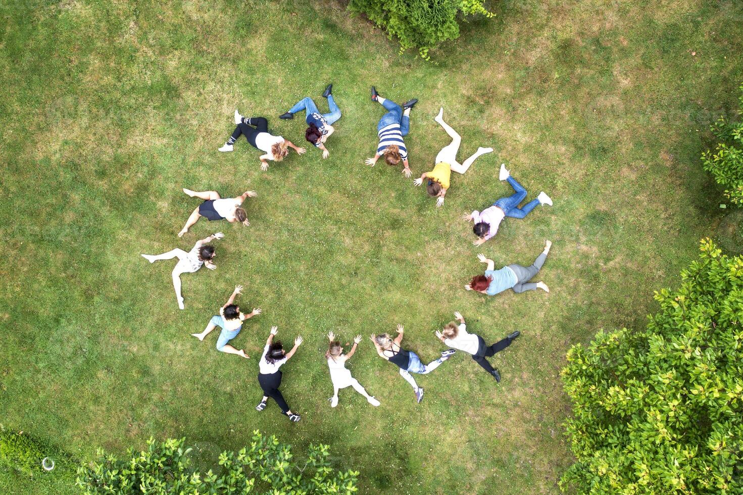 Top view of people standing in circle on green grass doing exercises photo