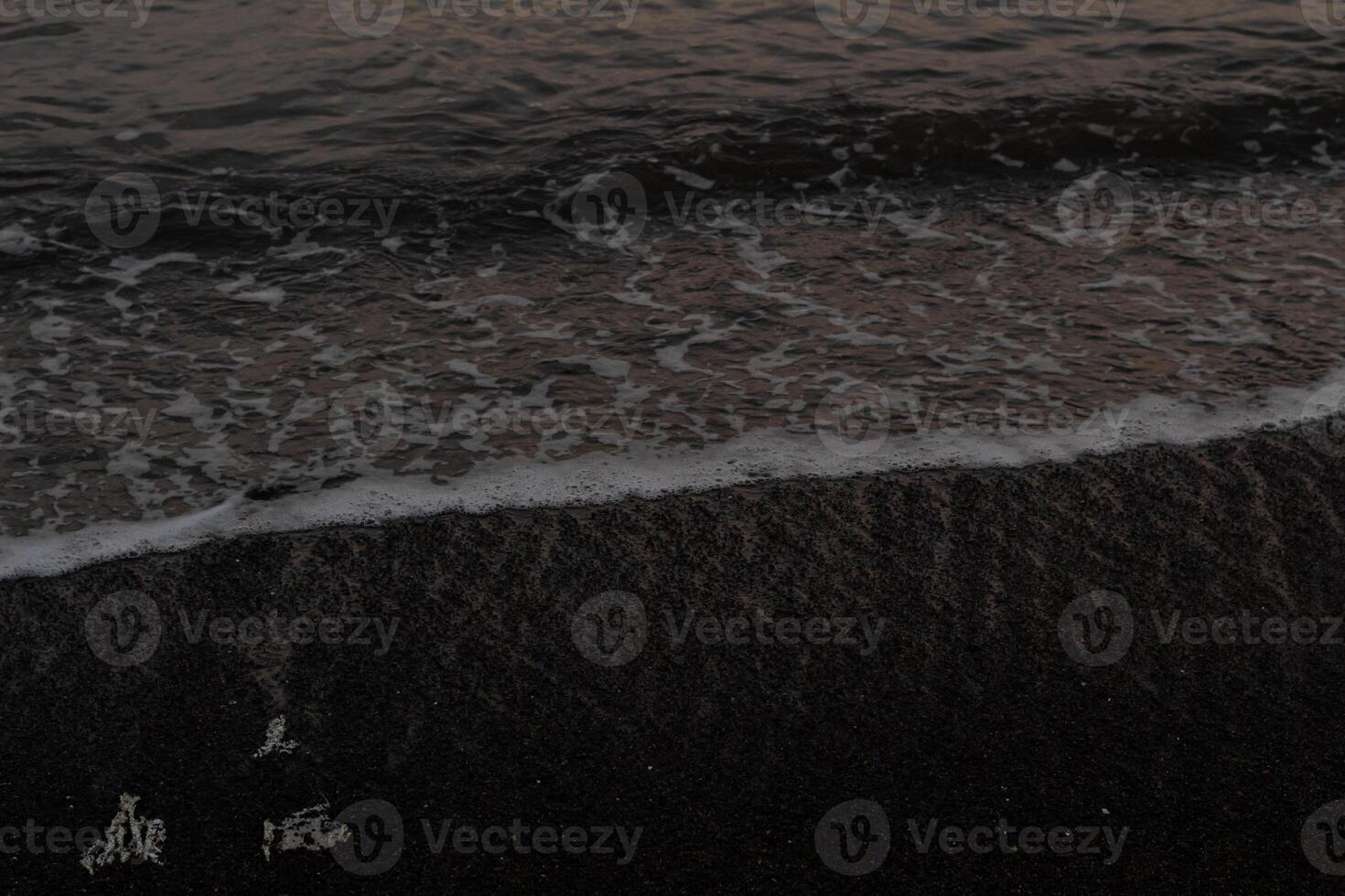 Black pebble beach with small waves photo