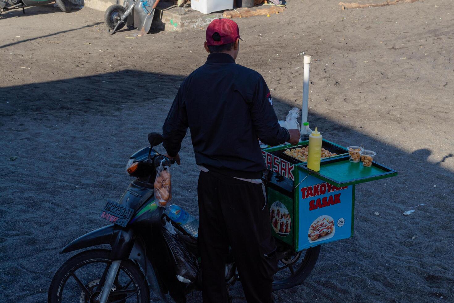 Takoyaki seller sells using a motorbike at Loang Baloq beach on July 14, 2024 - Lombok, Indonesia photo