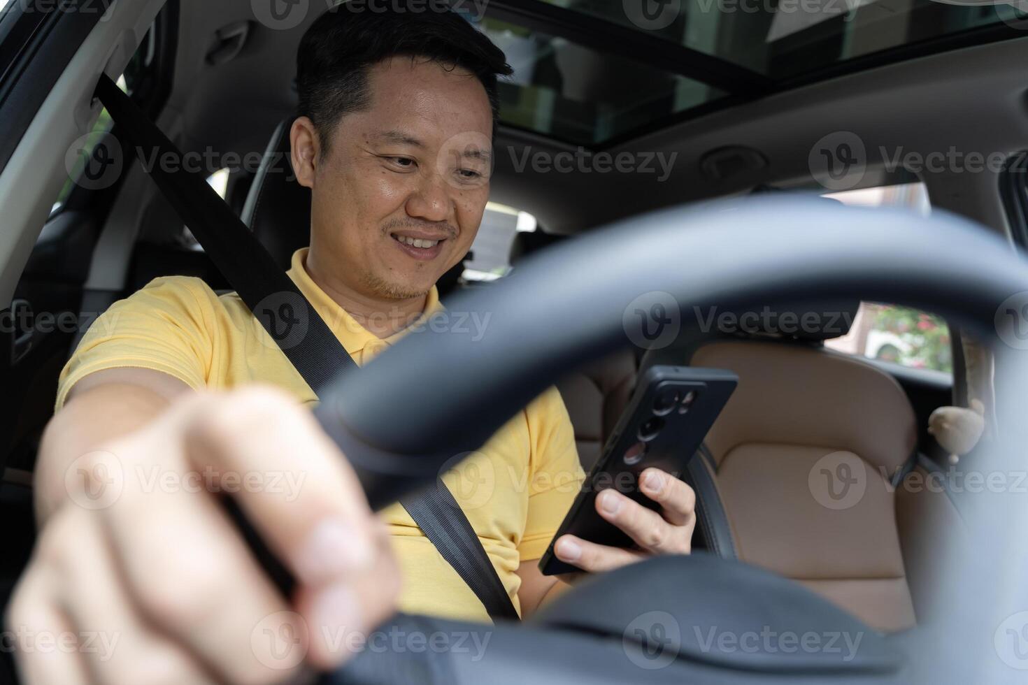 Cheerful arab driver man texting on smartphone while driving car. transport, vehicle and technology concept photo