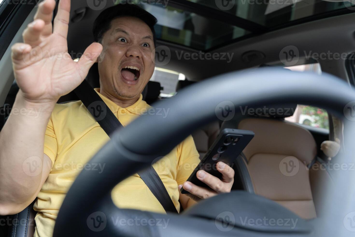 Terrified businessman having a car accident while using cell phone. Oh my God, I am going to crash. photo
