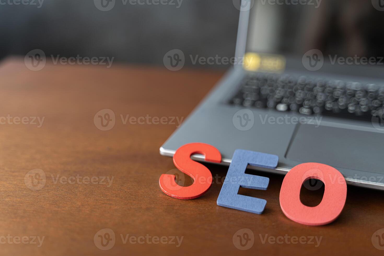 Wooden letter stands for SEO abbreviation lying on laptop at desk. Modern marketing buzzword SEO - Search engine optimisation. photo